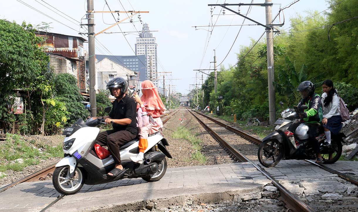 Pengendara motor melewati perlintasan kereta api sebidang di kawasan Pejagalan, Penjaringan, Jakarta, Jumat (19/6/2026).  (Beritanasional.com/Oke Atmaja)