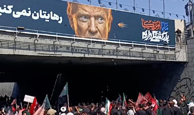 Reklame berisi foto Donald Trump dilempari batu oleh para pelayat Ali Khamenei di Teheran, Senin (6/7/2026). (BeritaNasional/Viory)