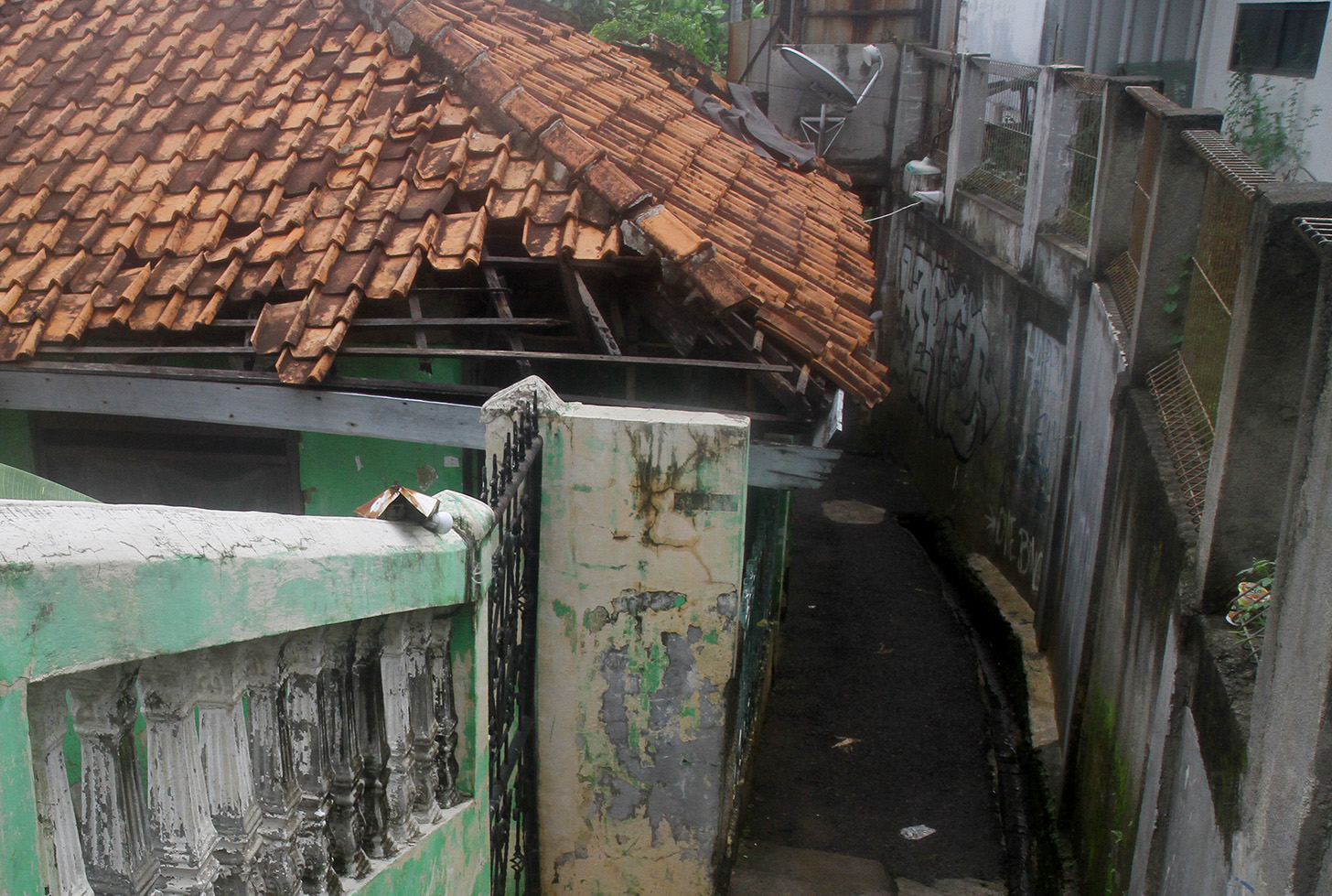 Warga berjalan di dekat rumah yang rusak akibat sering terendam banjir di Kampung Zombie Kawasan Cilitan, Jakarta, Selasa (18/6/2024).(BeritaNasional.Com/Oke Atmaja)