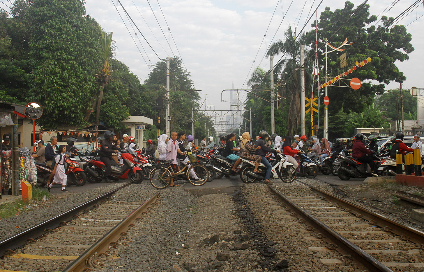Sejumlah pengendara motor melawan arah saat akan melintas di perlintasan kereta api di Menteng, Jakarta, Senin (27/5/2024). (BeritaNasional.Com/Oke Atmaja)