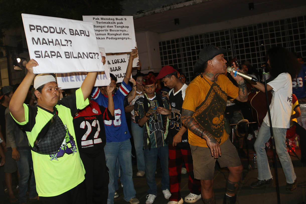 Massa aksi dari sejumlah seniman, konten creator dan masyarakat membawa poster dukungan produk UMKM konveksi pada Aksi Seni di Kota Tua, Jakarta, Minggu, Malam (16/11/2025).(Beritanasional.com/Oke Atmaja)
