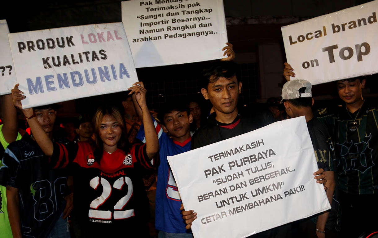 Massa aksi dari sejumlah seniman, konten creator dan masyarakat membawa poster dukungan produk UMKM konveksi pada Aksi Seni di Kota Tua, Jakarta, Minggu, Malam (16/11/2025).(Beritanasional.com/Oke Atmaja)