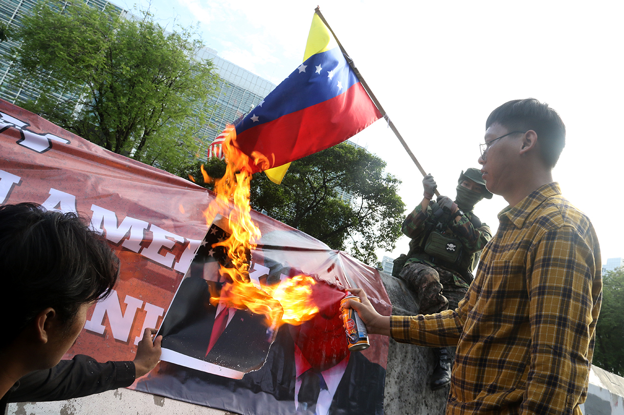 Pengunjuk rasa dari berbagai aliansi membakar bendera dan poster bergambar presiden AS Donald Trump saat menggelar aksi solidaritas untuk Venezuela di depan Kedutaan Besar Amerika Serikat, Jakarta, Selasa (6/1/2026).(Beritanasional.com/Oke Atmaja)