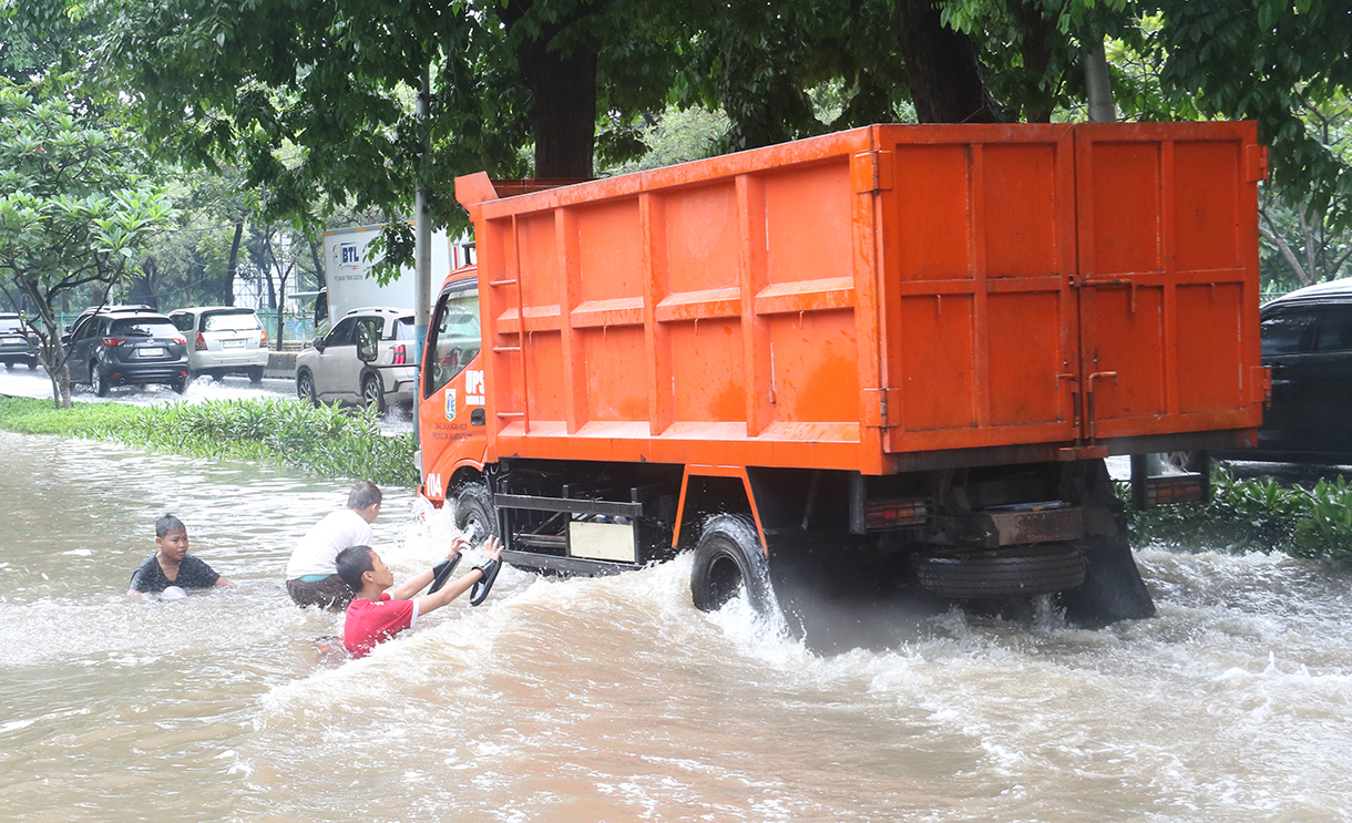 Seorang anak bermain di genangan air yang membanjiri jalan sekitar Cempaka Putih, Jakarta, Kamis(22/1/2026).(Beritanasional.com/Oke Atmaja)