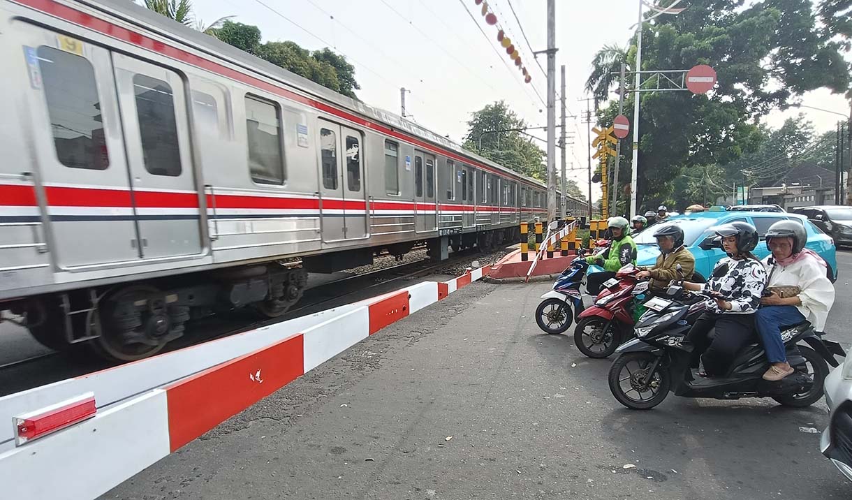 Angka Kecelakaan di Perlintasan Kereta Api Jakarta Pengendara motor menunggu kereta api melintas di Kawasan stasiun manggarai, Jakarta, Rabu(7/5/2025). (Beritanasional.com/Oke Atmaja)