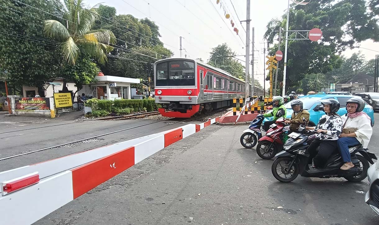 Angka Kecelakaan di Perlintasan Kereta Api Jakarta Pengendara motor menunggu kereta api melintas di Kawasan stasiun manggarai, Jakarta, Rabu(7/5/2025). (Beritanasional.com/Oke Atmaja)