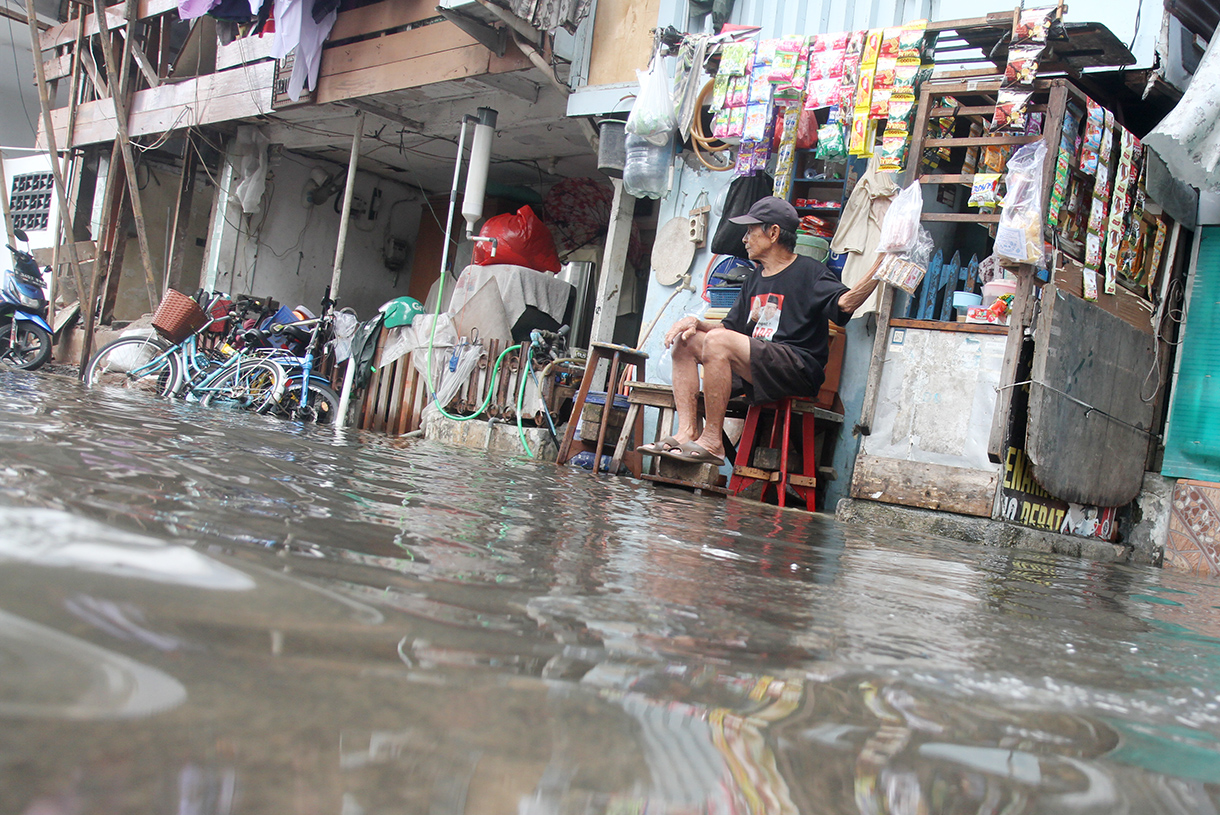 Warga menunggu warungnya di tengah banjir di Jelambar, Jakarta, Selasa (29/1/2025).(BeritaNasional/Oke Atmaja)