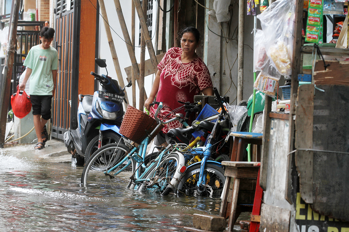 Warga menunggu warungnya di tengah banjir di Jelambar, Jakarta, Selasa (29/1/2025).(BeritaNasional/Oke Atmaja)