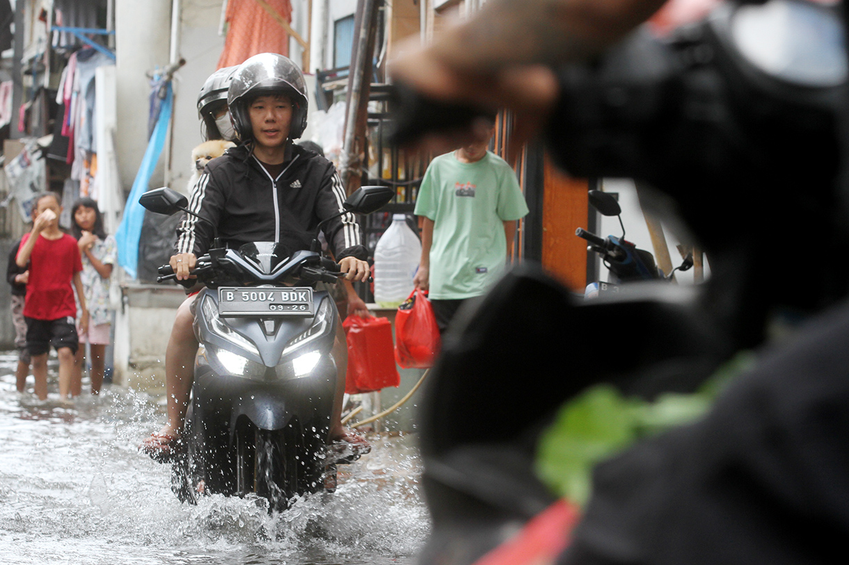 Warga menunggu warungnya di tengah banjir di Jelambar, Jakarta, Selasa (29/1/2025).(BeritaNasional/Oke Atmaja)