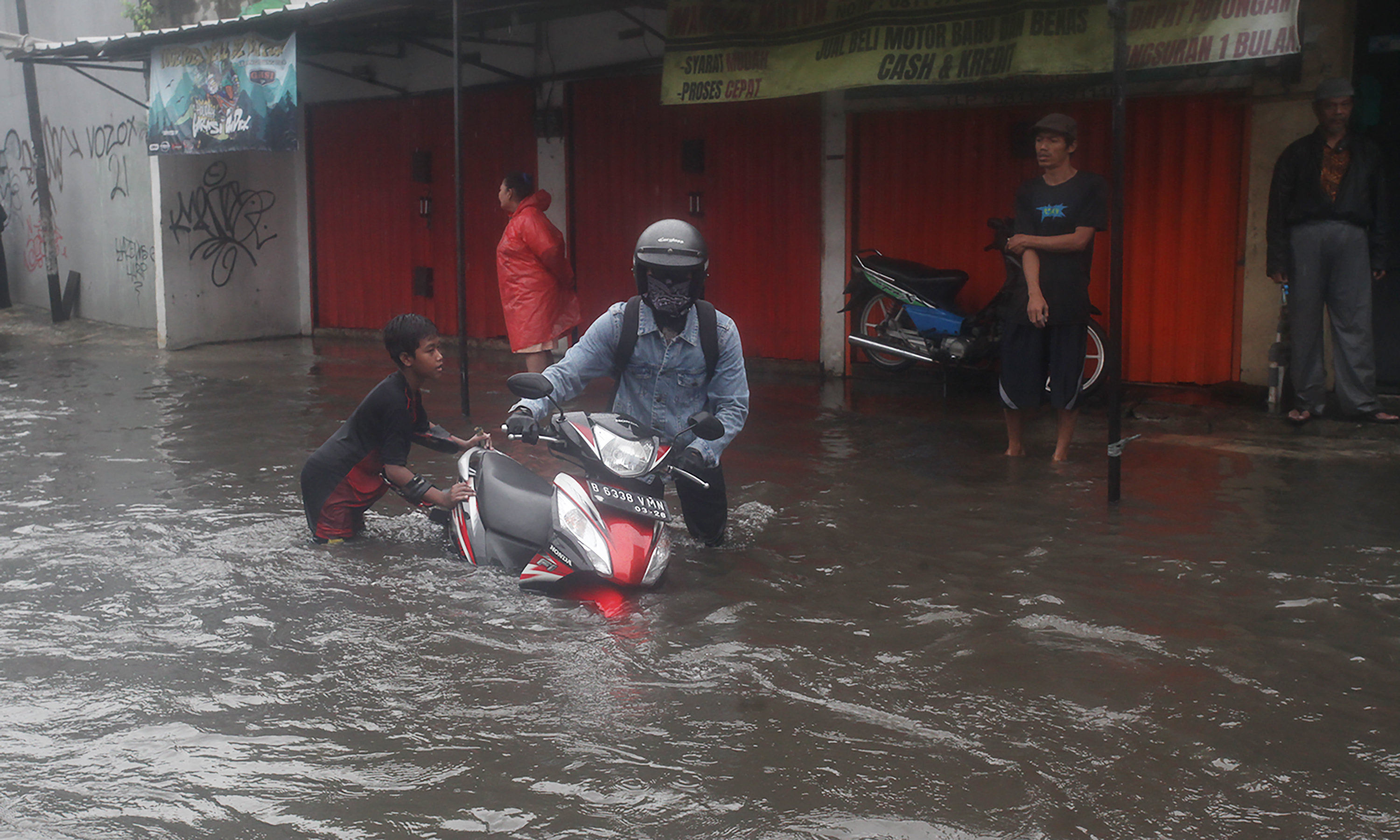 Pengojek gerobak mengangkut sepeda motor dan pengendaranya melintasi ruas Jalan Dr Soetomo di perbatasan Ciledug, Tangerang dengan Joglo, Jakarta Barat, Jumat (22/3/2024).(IndonesiaGlobe/Oke Atmaja)