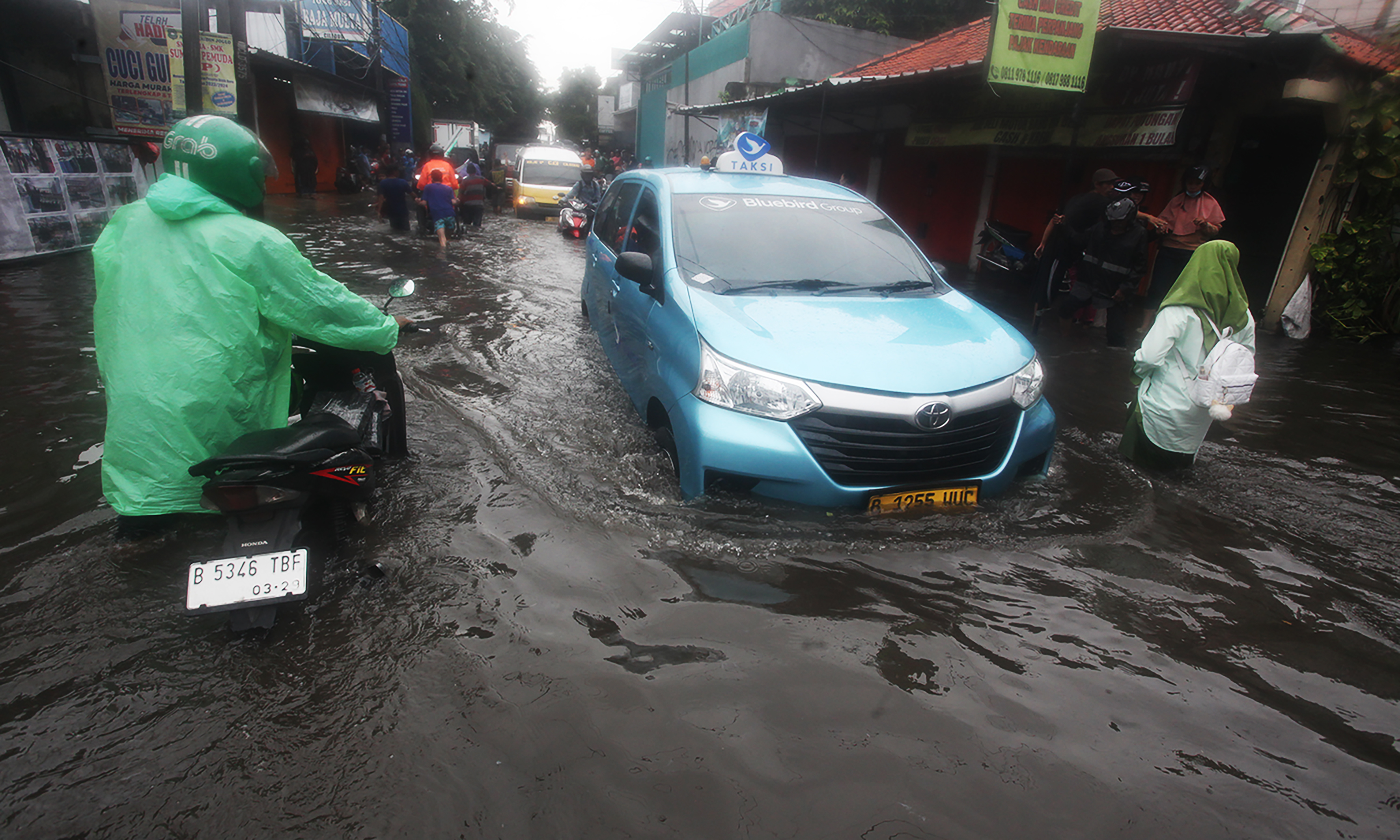 Pengojek gerobak mengangkut sepeda motor dan pengendaranya melintasi ruas Jalan Dr Soetomo di perbatasan Ciledug, Tangerang dengan Joglo, Jakarta Barat, Jumat (22/3/2024).(IndonesiaGlobe/Oke Atmaja)