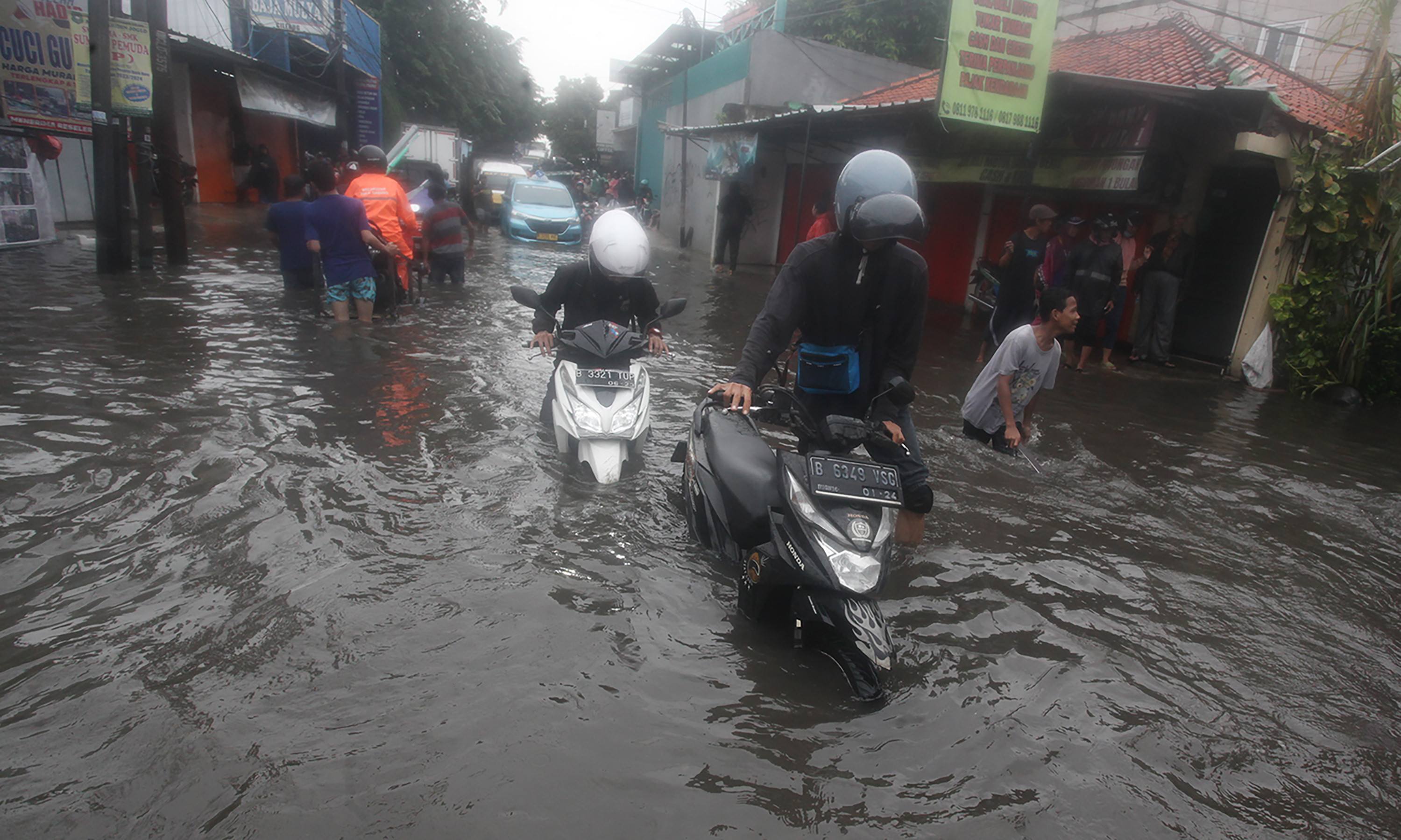 Pengojek gerobak mengangkut sepeda motor dan pengendaranya melintasi ruas Jalan Dr Soetomo di perbatasan Ciledug, Tangerang dengan Joglo, Jakarta Barat, Jumat (22/3/2024).(IndonesiaGlobe/Oke Atmaja)