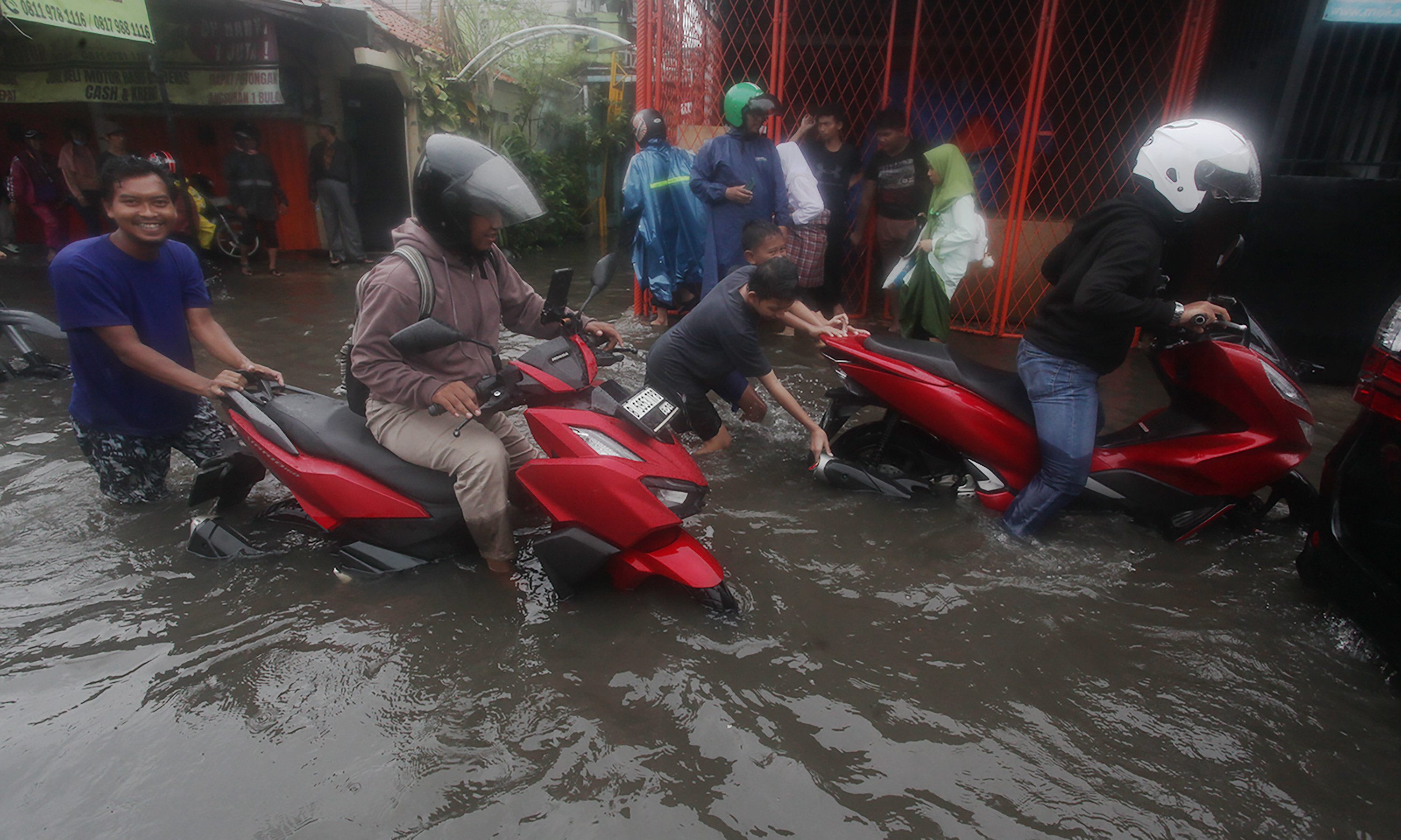 Pengojek gerobak mengangkut sepeda motor dan pengendaranya melintasi ruas Jalan Dr Soetomo di perbatasan Ciledug, Tangerang dengan Joglo, Jakarta Barat, Jumat (22/3/2024).(IndonesiaGlobe/Oke Atmaja)