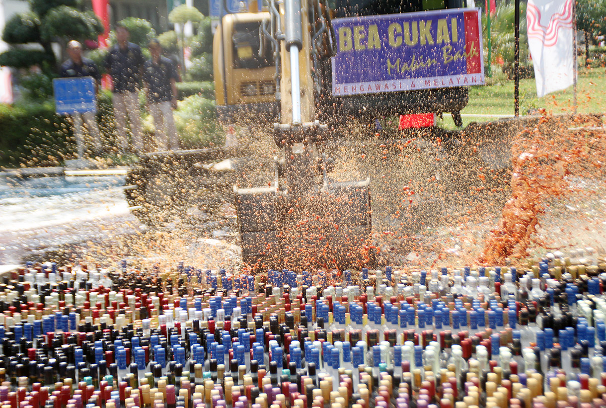 Petugas menggunakan alat berat eskavator saat memusnahkan minuman keras ilegal hasil penindakan di Kantor Pusat Bea Cukai, Jakarta Timur,Rabu (31/7/2024). (BeritaNasional.com/Oke Atmaja)