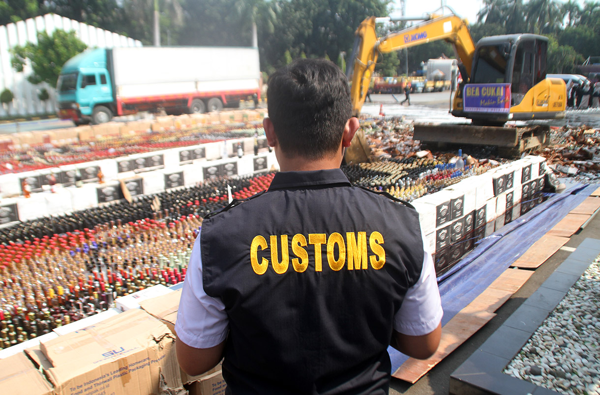 Petugas menggunakan alat berat eskavator saat memusnahkan minuman keras ilegal hasil penindakan di Kantor Pusat Bea Cukai, Jakarta Timur,Rabu (31/7/2024). (BeritaNasional.com/Oke Atmaja)