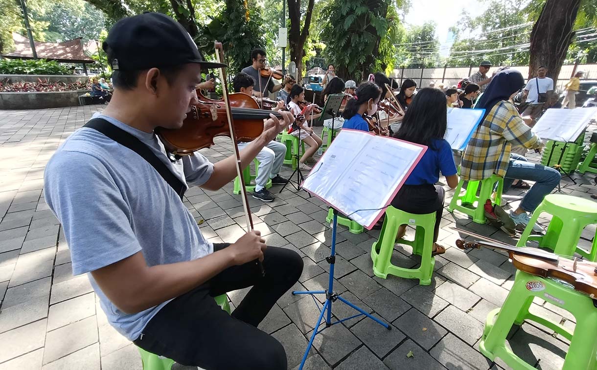 Warga bermain alat musik biola di Taman Suropati, Jakarta, Minggu (19/1/2024).  (BeritaNasional.com/Oke Atmaja)