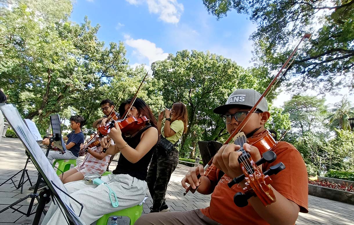 Warga bermain alat musik biola di Taman Suropati, Jakarta, Minggu (19/1/2024).  (BeritaNasional.com/Oke Atmaja)