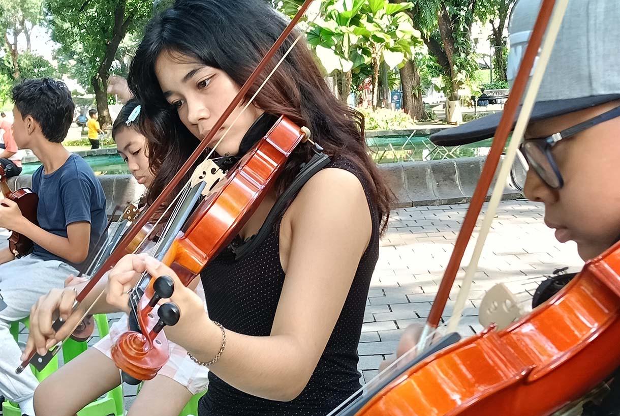 Warga bermain alat musik biola di Taman Suropati, Jakarta, Minggu (19/1/2024).  (BeritaNasional.com/Oke Atmaja)