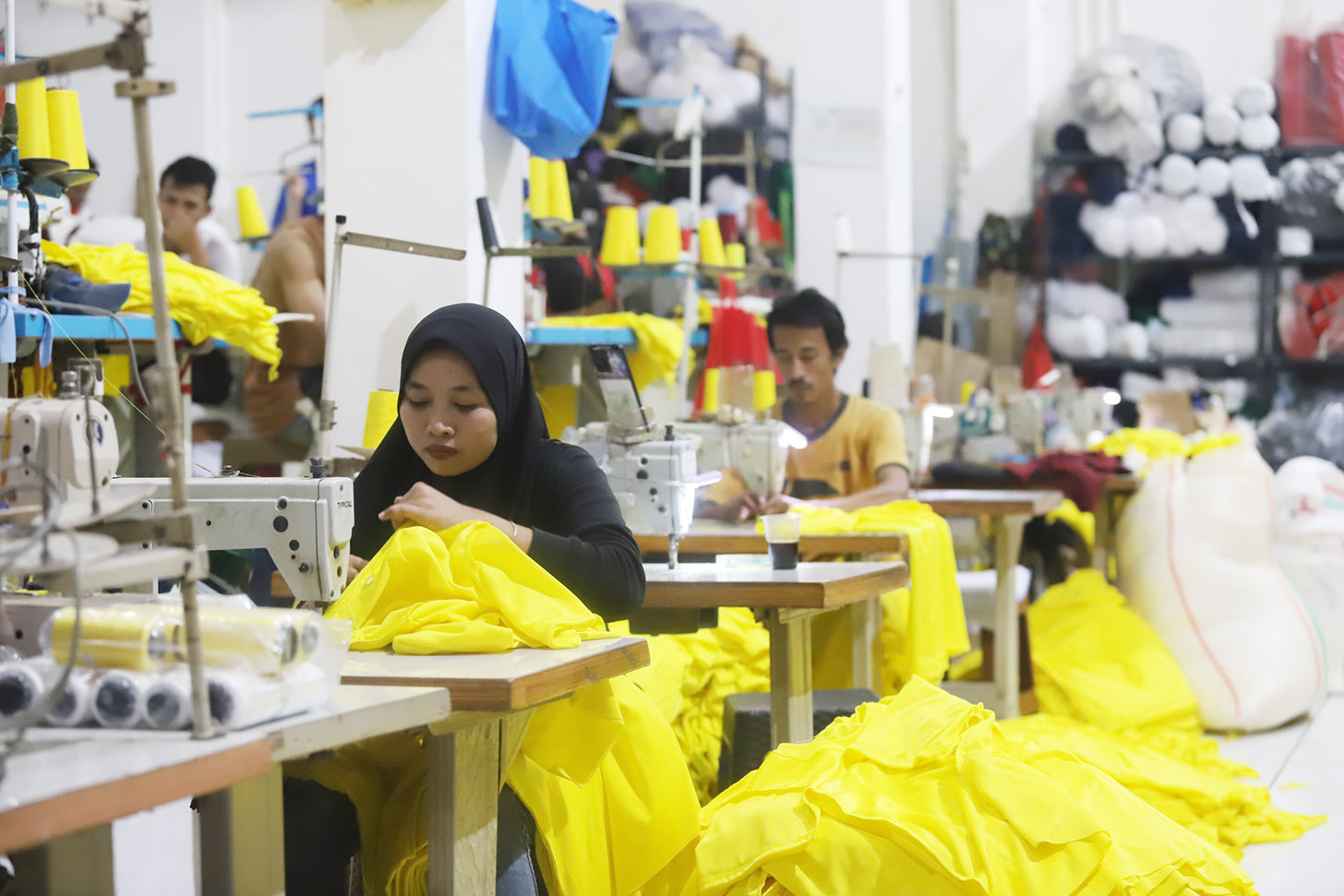 Sejumlah pekerja menjahit pesanan kaos di  konveksi Sinergi Adv, kawasan Srengseng Sawah, Jakarta, Minggu (7/7/2024). (BeritaNasional.com/Oke Atmaja)