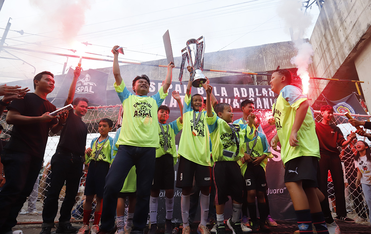 Sejumlah anak yang tergabung dalam tim Blue Lion mengangkat piala usai bertanding pada Liga Aspal di kawasan Menteng, Jakarta, Sabtu (18/7/2026). (Beritanasional.com/Oke Atmaja)