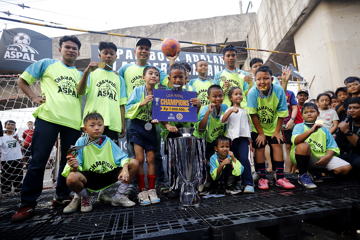 Sejumlah anak yang tergabung dalam tim Blue Lion mengangkat piala usai bertanding pada Liga Aspal di kawasan Menteng, Jakarta, Sabtu (18/7/2026). (Beritanasional.com/Oke Atmaja)