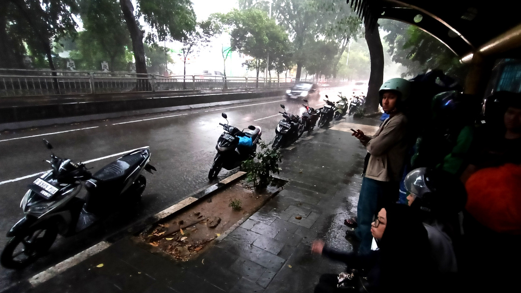 Warga memakai payung melintas di jembatan Stasiun Karet, Jakarta, Sabtu (4/4/2026). (Beritanasional.com/Oke Atmaja)