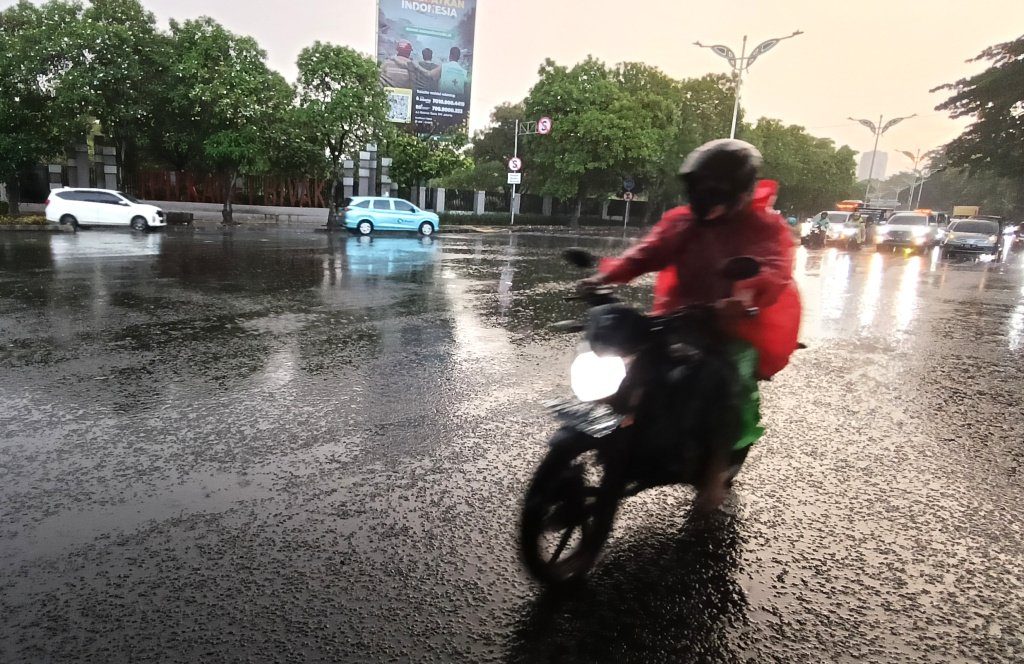 Warga memakai payung melintas di jembatan Stasiun Karet, Jakarta, Sabtu (4/4/2026). (Beritanasional.com/Oke Atmaja)
