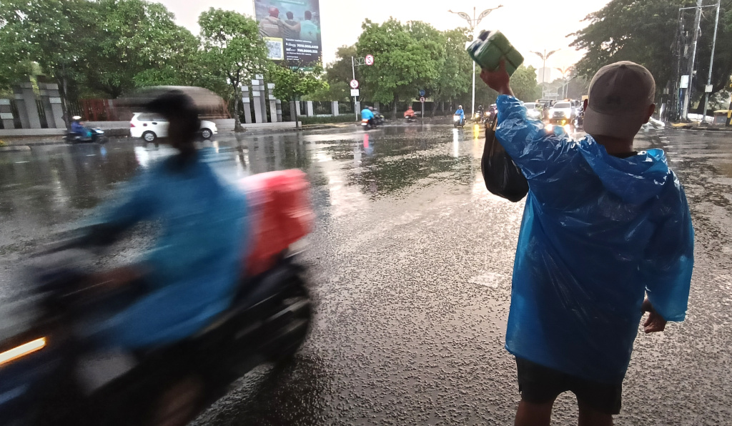 Warga memakai payung melintas di jembatan Stasiun Karet, Jakarta, Sabtu (4/4/2026). (Beritanasional.com/Oke Atmaja)