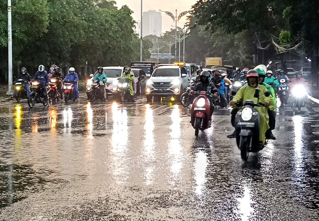 Warga memakai payung melintas di jembatan Stasiun Karet, Jakarta, Sabtu (4/4/2026). (Beritanasional.com/Oke Atmaja)