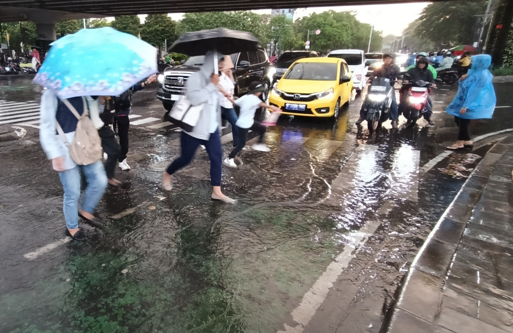 Warga memakai payung melintas. (Beritanasional.com/Oke Atmaja)