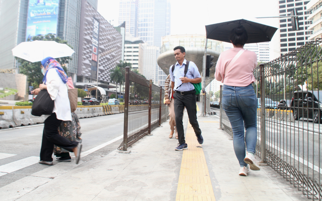 Aktivitas warga saat menggunakan payung melintas di kawasan Sudirman, Jakarta Pusat, Rabu (30/10/2024). .(Beritanasional.com/Oke Atmaja)