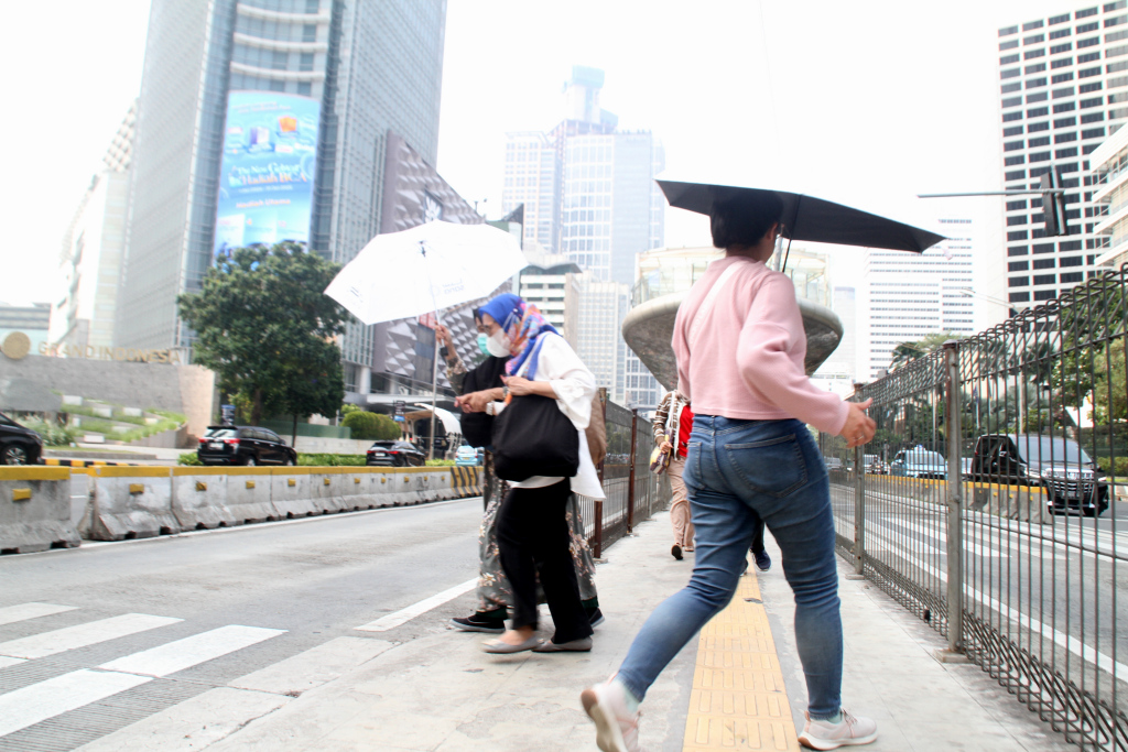 Aktivitas warga saat menggunakan payung melintas di kawasan Sudirman, Jakarta Pusat, Rabu (30/10/2024). .(Beritanasional.com/Oke Atmaja)