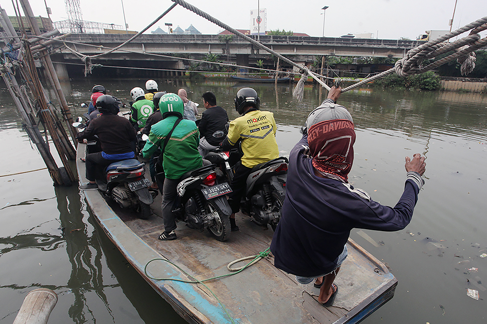 Warga berkendaraan motor saat menyebrang menggunakan perahu eret di Jakarta. (BeritaNasional/Elvis Sendouw)