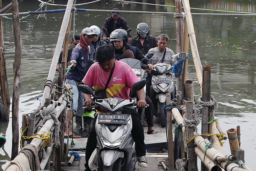 Warga berkendaraan motor saat menyebrang menggunakan perahu eret di Jakarta. (BeritaNasional/Elvis Sendouw)