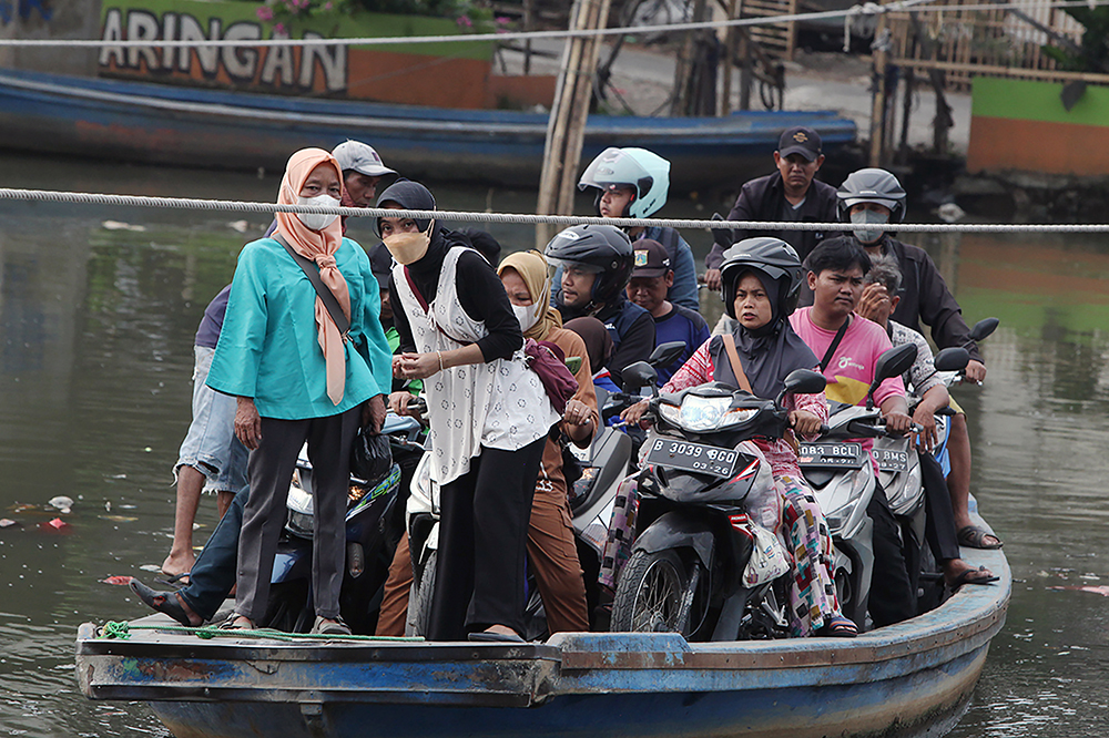 Warga berkendaraan motor saat menyebrang menggunakan perahu eret di Jakarta. (BeritaNasional/Elvis Sendouw)