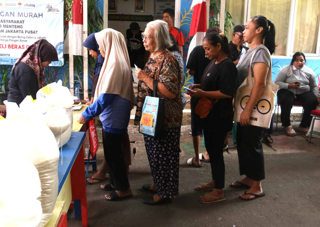 Warga memikul beras usai mengambil bantuan pangan gratis di Balai RW 03 Kelurahan Menteng, Jakarta, Rabu, (12/11/2025). (Berita nasional.com/Oke Atmaja)