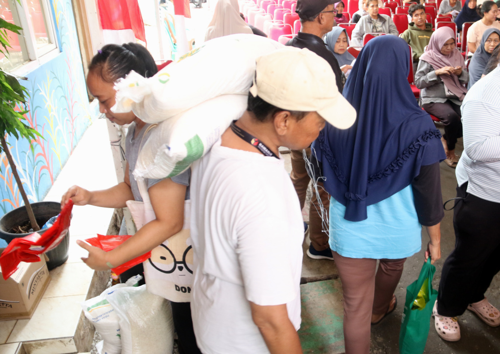 Warga memikul beras usai mengambil bantuan pangan gratis di Balai RW 03 Kelurahan Menteng, Jakarta, Rabu, (12/11/2025). (Berita nasional.com/Oke Atmaja)