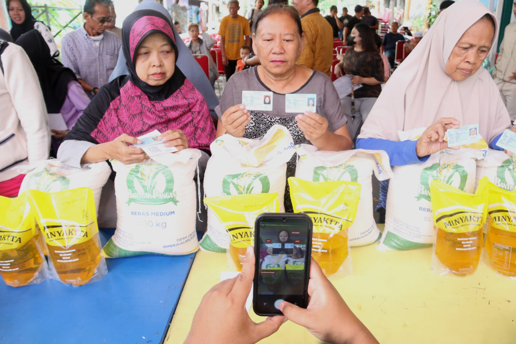 Warga memikul beras usai mengambil bantuan pangan gratis di Balai RW 03 Kelurahan Menteng, Jakarta, Rabu, (12/11/2025). (Berita nasional.com/Oke Atmaja)