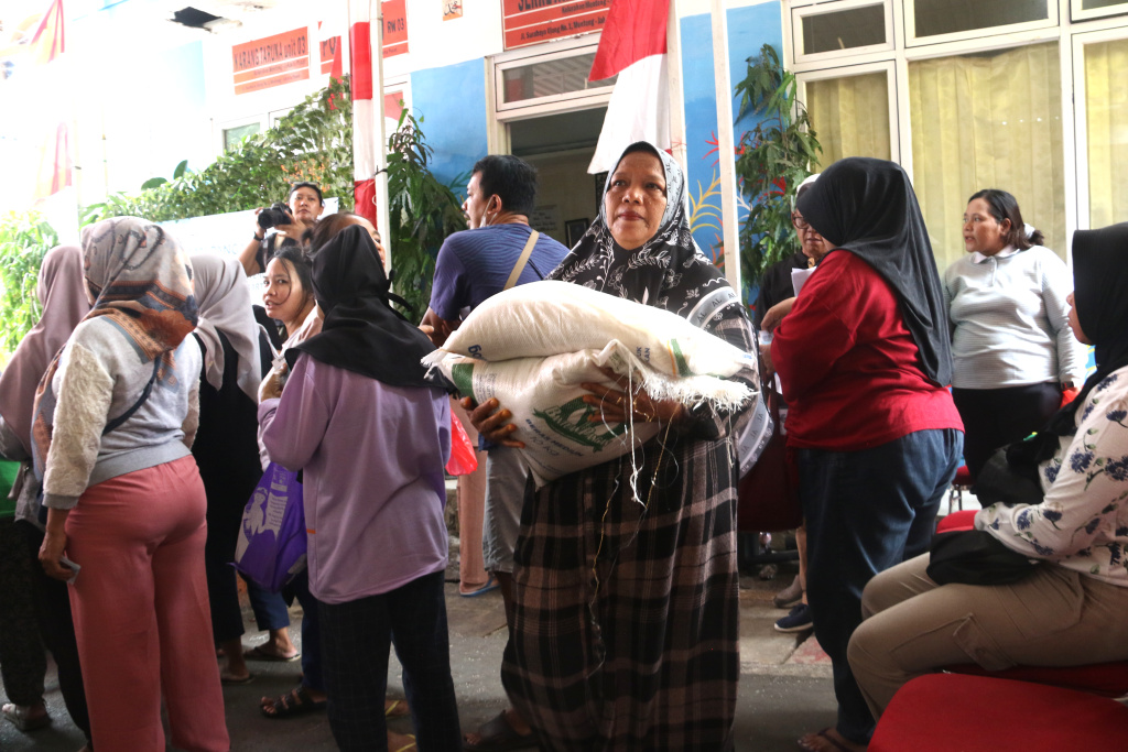 Warga memikul beras usai mengambil bantuan pangan gratis di Balai RW 03 Kelurahan Menteng, Jakarta, Rabu, (12/11/2025). (Berita nasional.com/Oke Atmaja)