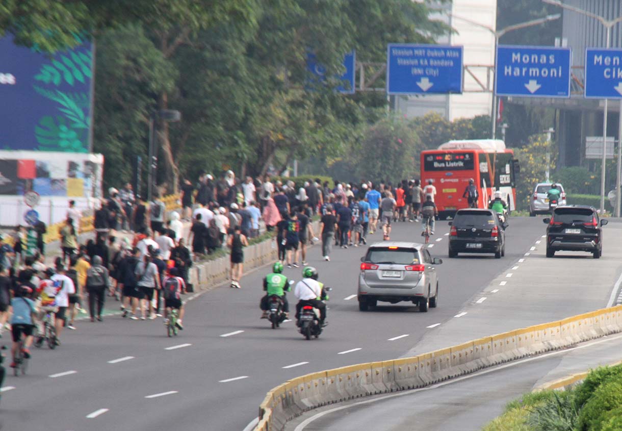 Pengendara motor melintas berdampingan dengan warga yang sedang berolahraga di kawasan Bundaran HI, Jakarta, Minggu (31/5/2026).(Beritanasional.com/Oke Atmaja)