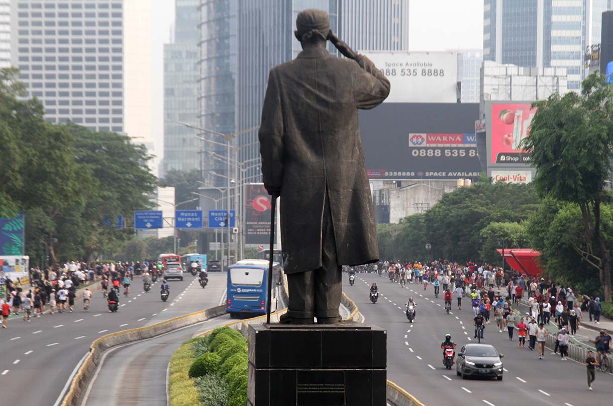 Pengendara motor melintas berdampingan dengan warga yang sedang berolahraga di kawasan Bundaran HI, Jakarta, Minggu (31/5/2026).(Beritanasional.com/Oke Atmaja)