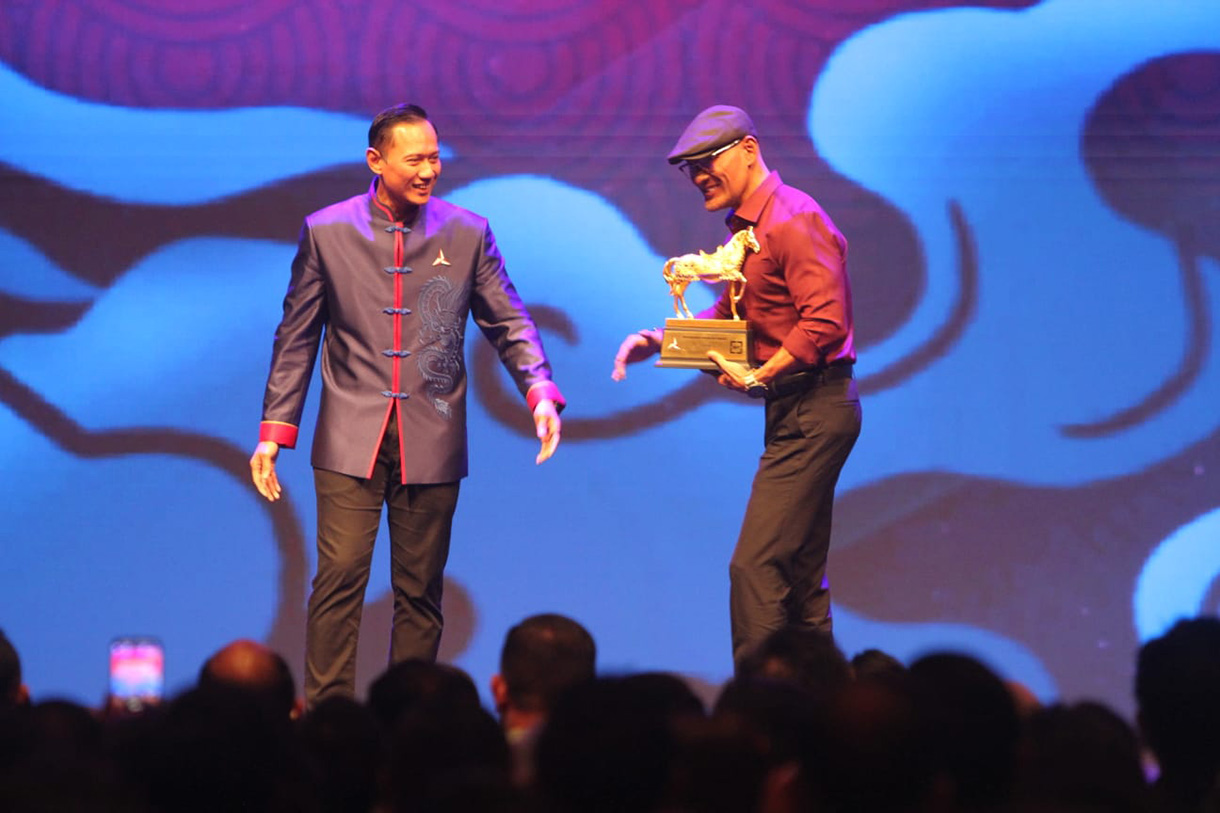 Ketua Umum Partai Demokrat Agus Harimurti Yudhoyono (kiri) memberikan penghargaan kepada Stafsus Menhan Bidang Komunikasi dan Publik Deddy Corbuzier saat Perayaan Imlek Nasional bertema Harmoni Nusantara di Djakarta Theater, Jakarta, Rabu (18/2/2026).(Beritanasional.com/Oke Atmaja)