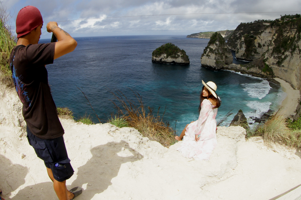 Pengunjung berfoto berlatar pantai Diamond Beach di Nusa Penida, Bali, Minggu (2/6/2024).  (BeritaNasional.Com/Oke Atmaja)