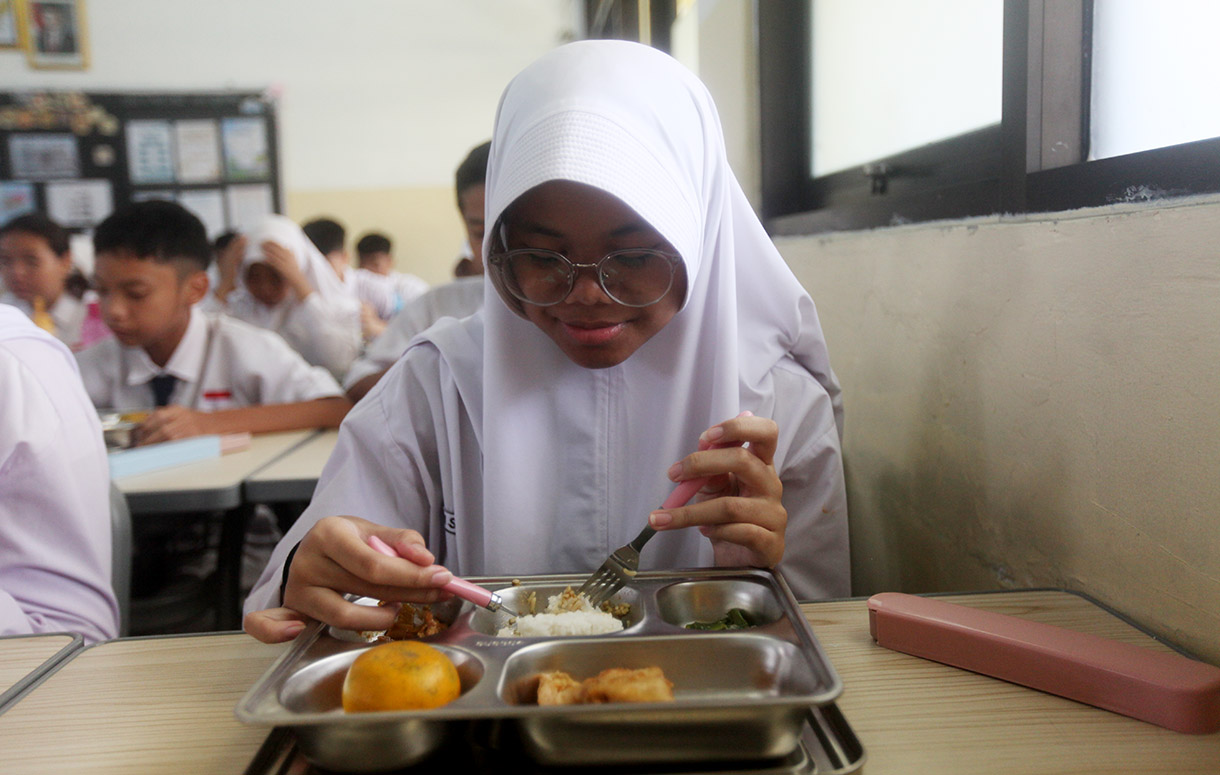 Siswa menyantap makanan bergizi gratis di SMP Barunawati Slipi, Jakarta, Senin (6/1/2025).(BeritaNasional.com/Oke Atmaja)