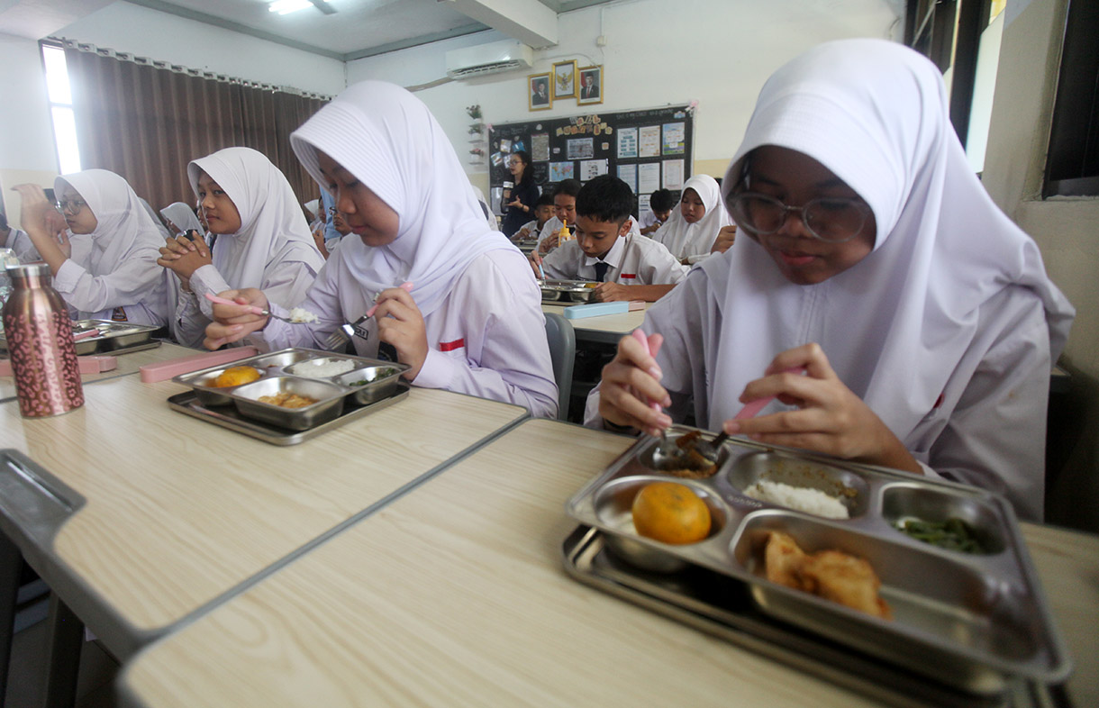 Siswa menyantap makanan bergizi gratis di SMP Barunawati Slipi, Jakarta, Senin (6/1/2025).(BeritaNasional.com/Oke Atmaja)