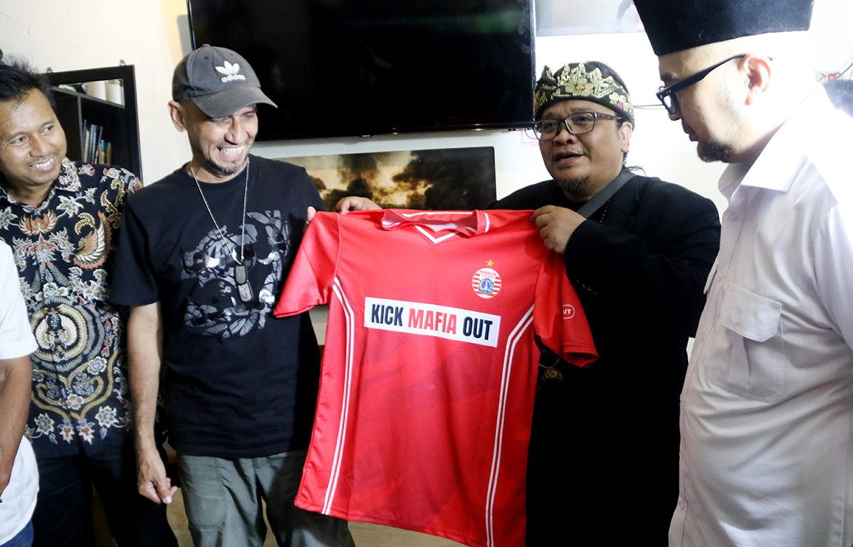 CEO Sinergi ADV Nusantara Prama Tirta (ketiga Kiri) memberikan baju kepada Seporter The Jakmania Garis Keras Bang Irfan (keempat Kanan) yang disaksikan oleh Ikatan Pengusaha Konveksi Berkarya (IPKB), Asosiasi Pertekstilan Indonesia (API), Asosiasi Produsen Serat & Benang Filamen Indonesia (APSyFI), Aliansi Industri Kecil Menengah Indonesia (AIKMI) di Kedai Coffe Halaman, Jakarta, Jumat (28/11/2025).  (Beritanasional.com/Oke Atmaja)