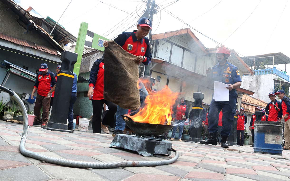 Petugas mengarahkan seorang warga yang menggunakan alat pemadam api ringan (APAR) saat simulasi penanggulangan kebakaran di Perkampungan Menteng Tenggulun, Jakarta, Kamis (9/10/2025)  (Beritanasional.com/Oke Atmaja)