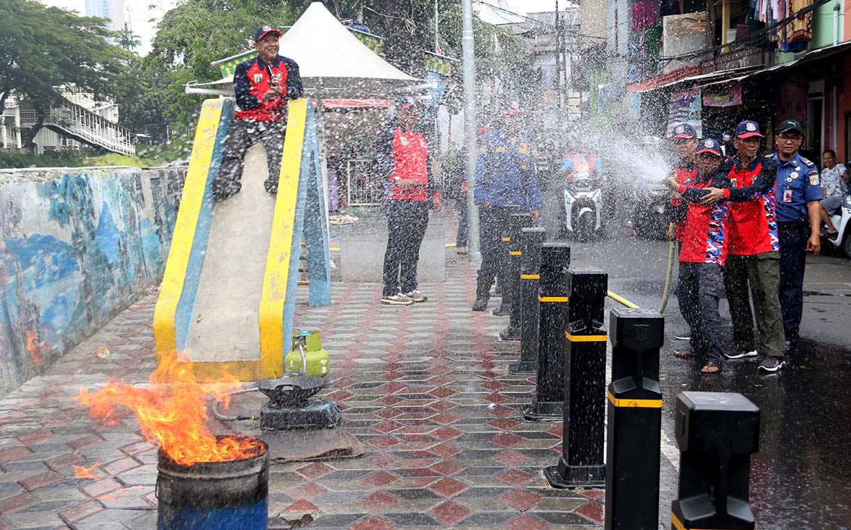 Petugas mengarahkan seorang warga yang menggunakan alat pemadam api ringan (APAR) saat simulasi penanggulangan kebakaran di Perkampungan Menteng Tenggulun, Jakarta, Kamis (9/10/2025)  (Beritanasional.com/Oke Atmaja)