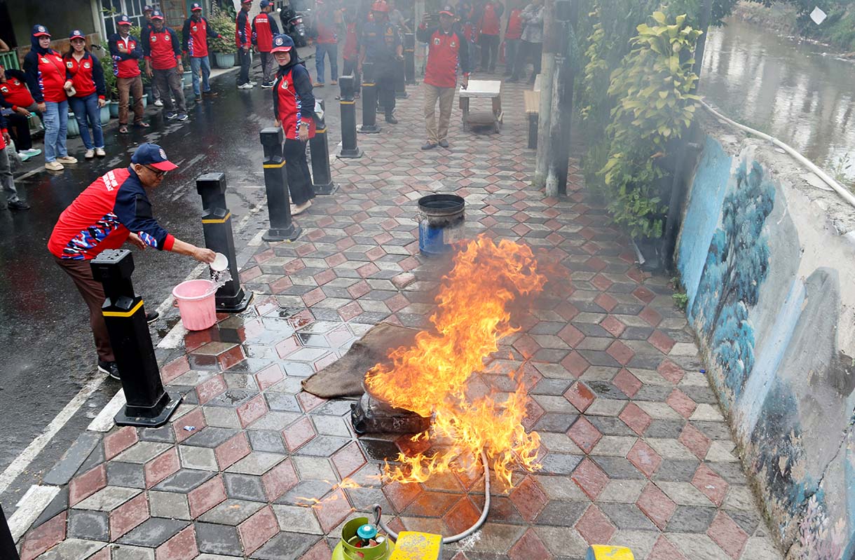 Petugas mengarahkan seorang warga yang menggunakan alat pemadam api ringan (APAR) saat simulasi penanggulangan kebakaran di Perkampungan Menteng Tenggulun, Jakarta, Kamis (9/10/2025)  (Beritanasional.com/Oke Atmaja)