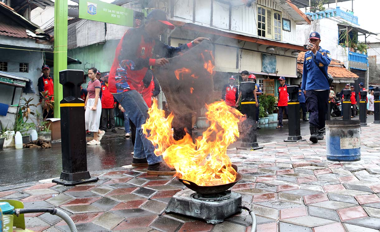 Petugas mengarahkan seorang warga yang menggunakan alat pemadam api ringan (APAR) saat simulasi penanggulangan kebakaran di Perkampungan Menteng Tenggulun, Jakarta, Kamis (9/10/2025)  (Beritanasional.com/Oke Atmaja)